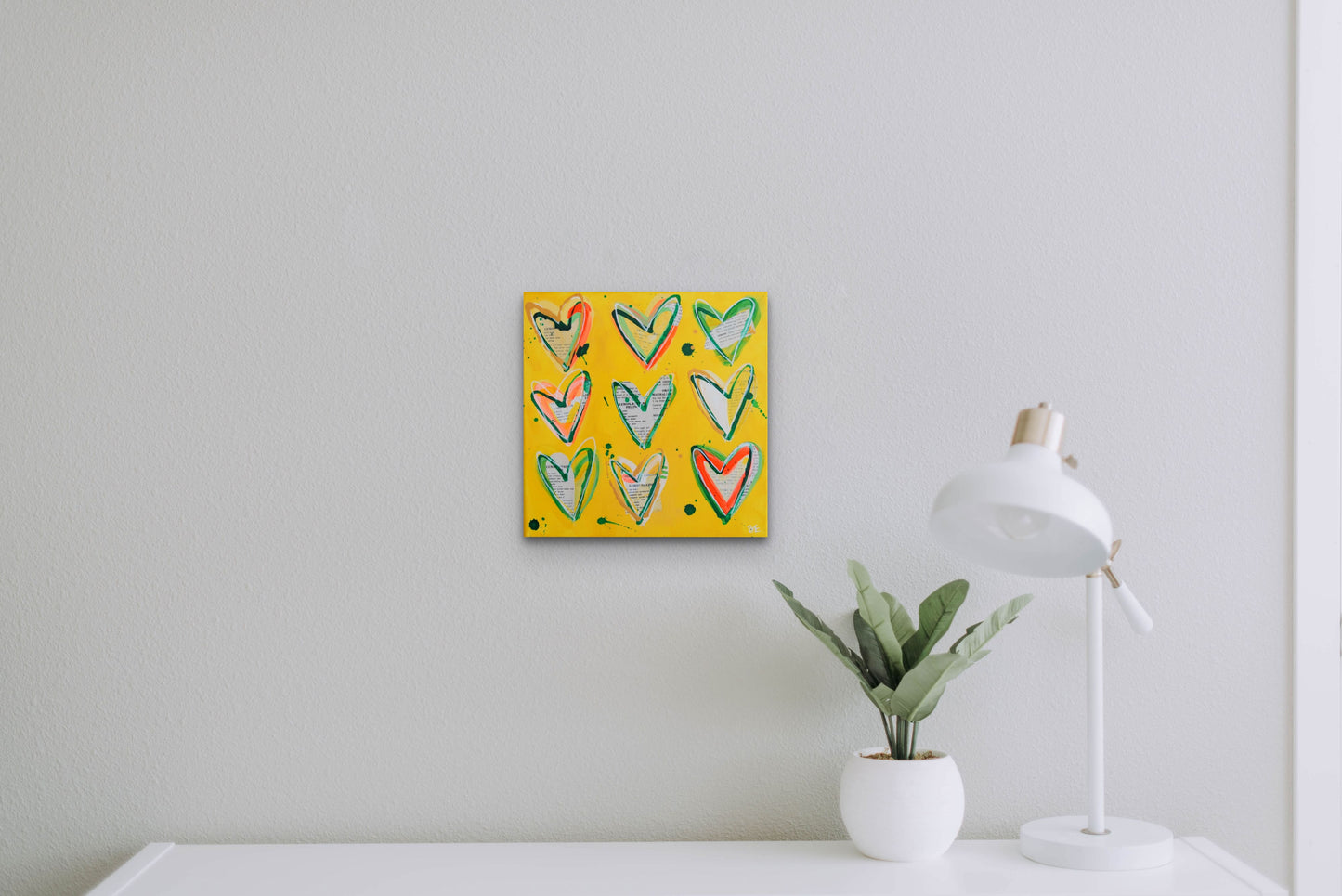 LEMON TREE. Original mixed media on canvas with vintage cookbook and hearts. Hanging on bright white wall with white desk, lamp, and plant in foreground.